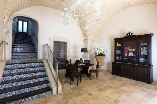 a room with a staircase and a table and a chandelier at Palazzo Conti Camere & Suites in Scicli