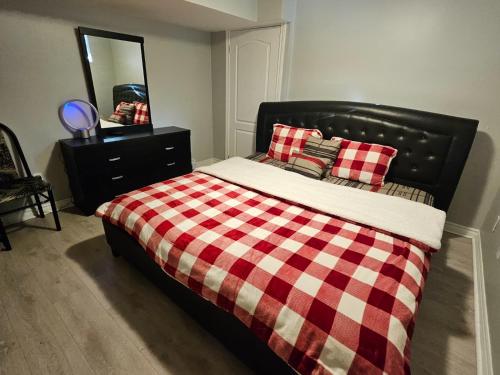 een bed met een geruite deken en een spiegel bij Peace Apartment in Brampton