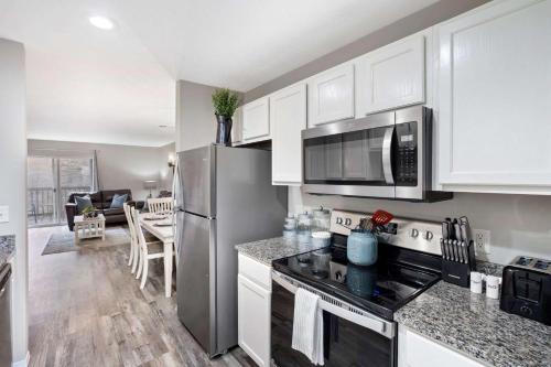 a kitchen with white cabinets and a stainless steel refrigerator at Rockwall Lodge - Close to Branson Strip in Branson