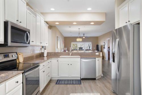 een keuken met witte kasten en een roestvrijstalen koelkast bij Lakefront Sanctuary - Table Rock Lake Adventures in Branson