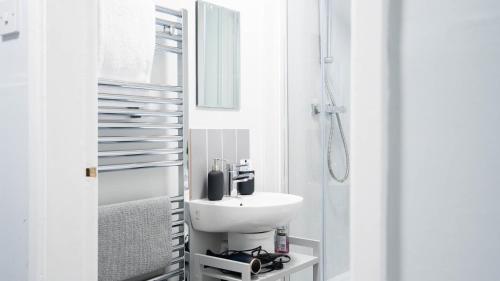 une salle de bain blanche avec un lavabo et une douche dans l'établissement Reardon Apartment Warwick - Sleeps 5 - Parking & Wifi, à Warwick