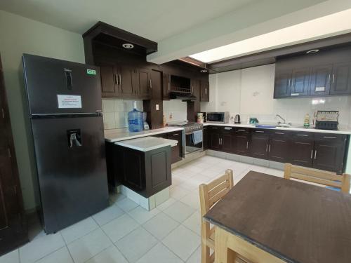 a large kitchen with a black refrigerator and a table at Jardin 85 Hostel in Morelia