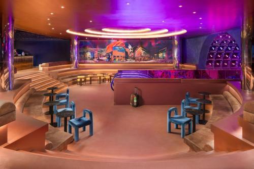 a room with chairs and a stage with purple lights at Moxy London Piccadilly Circus in London