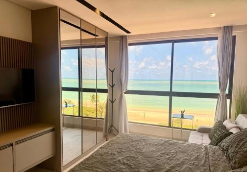 a bedroom with a large window with a view of the ocean at Flat Vista-Mar in Cabedelo