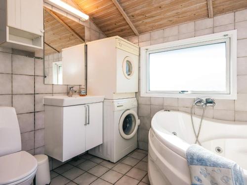 a bathroom with a tub sink and a washing machine at Seaside Haven with Spa - By Traum Ferienwohnungen in Sønder Bjert