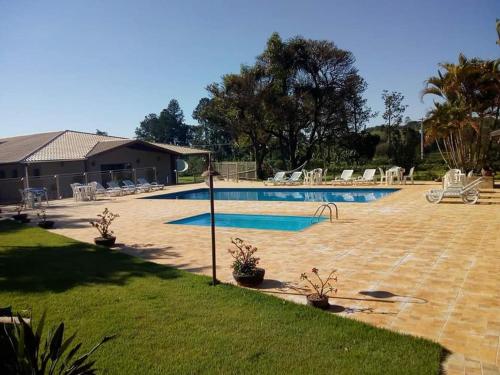 a swimming pool in a yard with chairs around it at Hotel Kaeru in Avaré