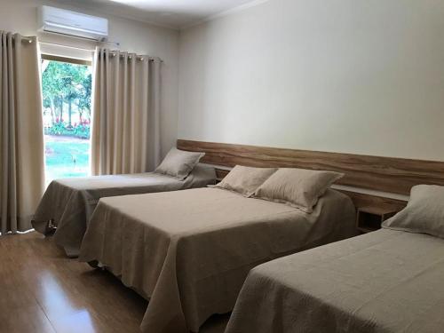 two beds in a room with a window at Hotel Kaeru in Avaré