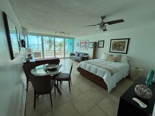 a bedroom with a bed and a table and a dining room at Ocean view Studio Marina Lanais in Fajardo