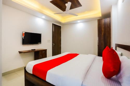 a bedroom with a bed with red pillows and a tv at Super Hotel O Kazhakkoottam Near Technopark Phase 3 in Trivandrum