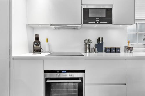 a white kitchen with a stove and a microwave at Luxury Villa by Hyde Park in London