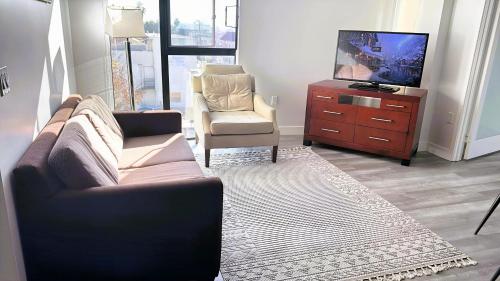 a living room with a couch and a chair and a tv at Melrose Luxe Retreat near The Grove in Los Angeles