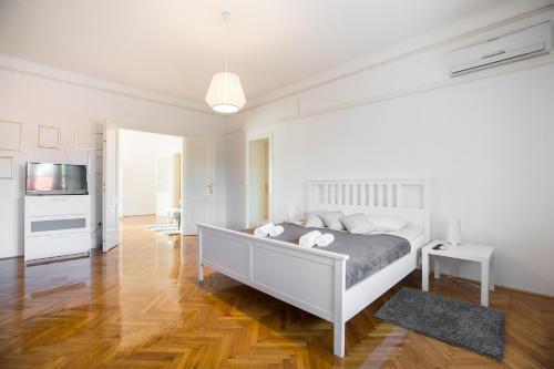 a white bedroom with a bed and a television at Apartment Ribnjak in Zagreb