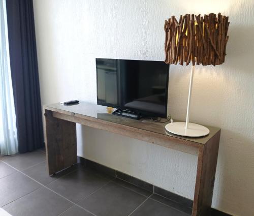 a desk with a television and a lamp in a room at Studio Le Sablé in Îlet à Christophe