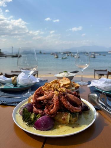 a plate of food on a table with wine glasses at Ponta Da Barca in Praia Vermelha