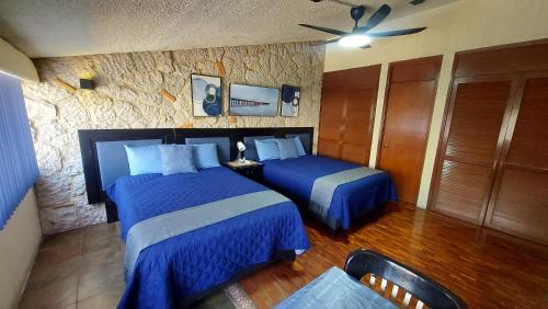 a bedroom with two beds and a stone wall at Habitación amplia cerca de Andares in Guadalajara