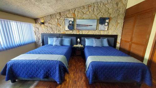two beds in a hotel room with blue comforters at Habitación amplia cerca de Andares in Guadalajara