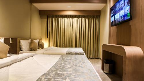 a hotel room with two beds and a flat screen tv at The Falcon Inn in Mumbai
