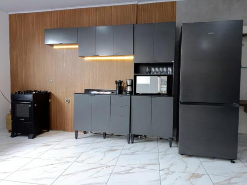 a kitchen with a black refrigerator and a microwave at Apartment on the 3rd floor, 10 minutes from the beach, railway and bus station in Vila Velha