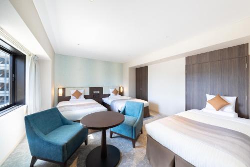 a hotel room with two beds and a table and chairs at Art Hotel Niigata Station in Niigata