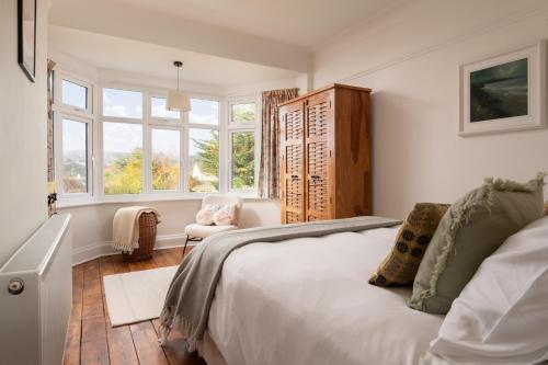a bedroom with a bed and a chair and windows at Summerfield in Conwy
