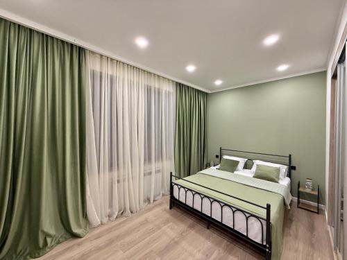 埃里温Charming Central Apartment with 2 Bedrooms & Balcony by Republic Square的一间卧室，挂着绿色窗帘，床上放着白色枕头。