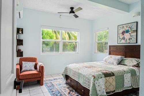 a bedroom with a bed and a chair and windows at Garden Apartment in Trinity