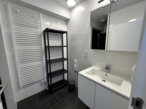 Un baño blanco con lavabo y espejo. en Westhinder I H30, en Koksijde