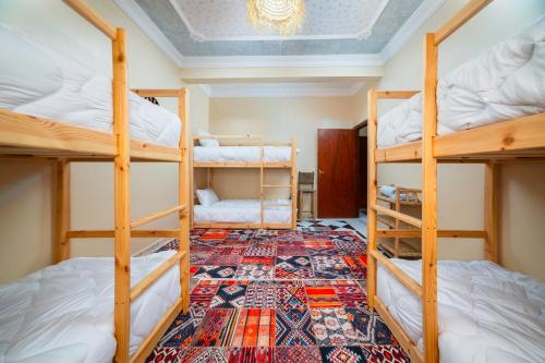 Habitación con 4 literas y alfombra. en Lumir Surf House, en Tamraght Ouzdar
