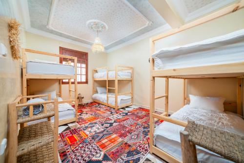 1 dormitorio con literas y alfombra en Lumir Surf House, en Tamraght Ouzdar