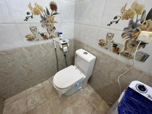 a bathroom with a toilet and flowers on the wall at شقة 3 غرف نوم وصالة 3 bedroom and living room apartment in Taif
