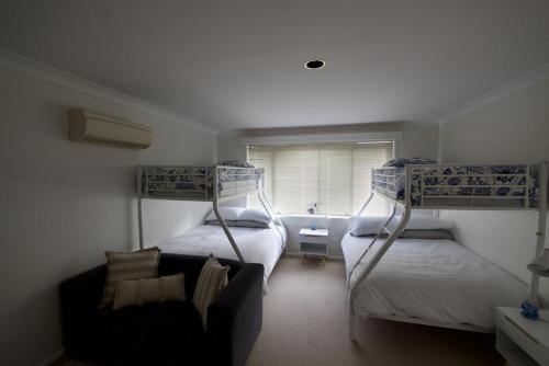 a bedroom with two bunk beds and a couch at Gravity Stayz in Batehaven