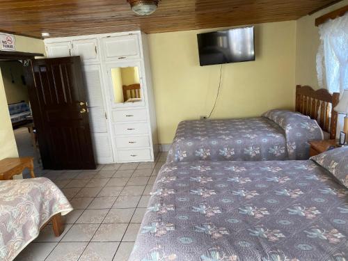 a bedroom with two beds and a tv on the wall at Casa Elia in Creel