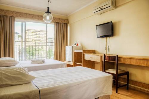 a hotel room with two beds and a television at Hotel Nacional Inn Poços de Caldas - Lazer completo e Gastronomia no Centro in Poços de Caldas