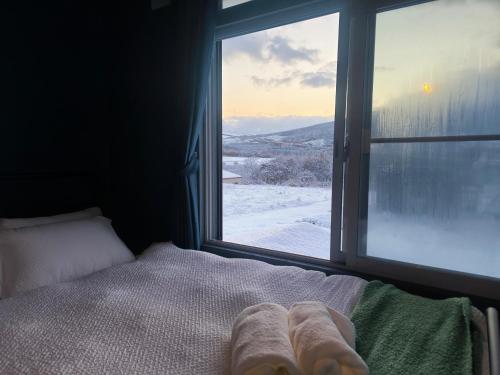 a bed in a room with a window with snow outside at Rusutsu Ski Stay111 in Rusutsu