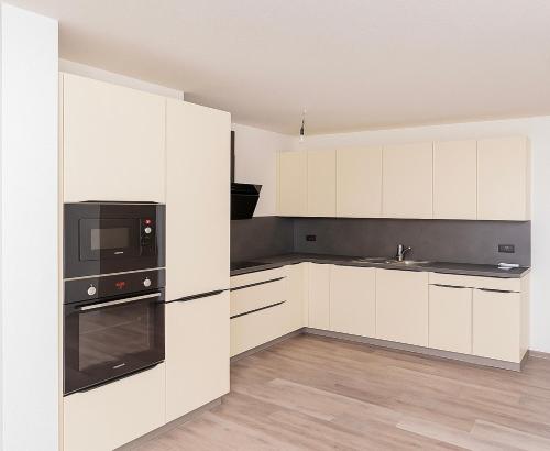 a kitchen with white cabinets and black appliances at Haus am Vogesenblick - Ihr Zimmer mit Aussicht für bis zu 3 Personen in Bad Bellingen