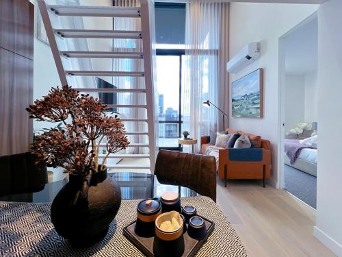 a living room with a table and a spiral staircase at Convenient Loft Modern Stay Central Box Hill in Box Hill