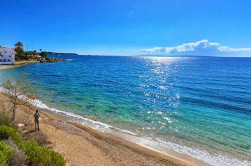 a person walking on a beach next to the ocean at sea soul house in Athens