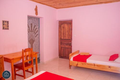 een slaapkamer met een bed, een bureau en een tafel bij Kambana Résidence in Ranomafana