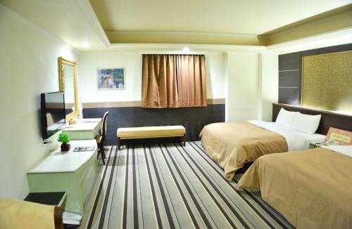 a hotel room with two beds and a desk at Ying Zhen Hotel in Taoyuan