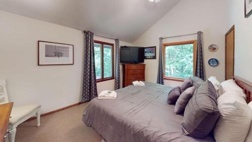 a bedroom with a bed and a tv and windows at Dean Hill Chalet in Killington