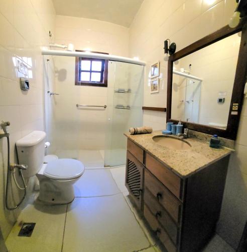 a bathroom with a toilet and a sink and a mirror at Encantos do mar in Arraial do Cabo