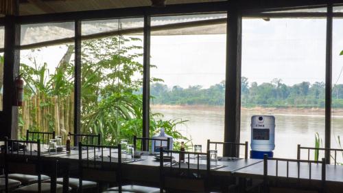a room with tables and chairs with a view of a river at Amazon Planet in Tambopata