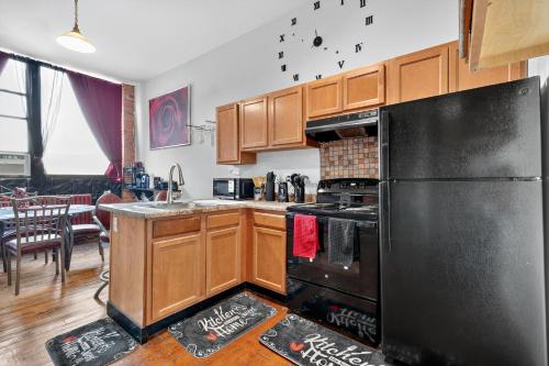 Una cocina con refrigerador negro y gabinetes de madera. en Beautiful 'Rose Themed' Loft Near Downtown Detroit apts, en Detroit