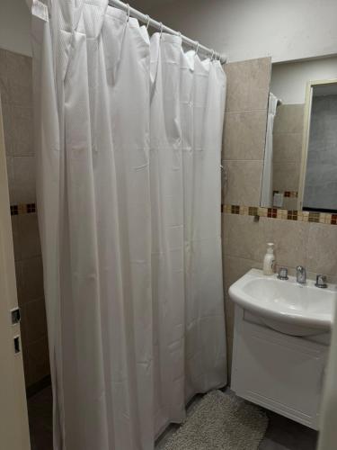 a bathroom with a white shower curtain and a sink at Duplex trelew para 3 in Trelew