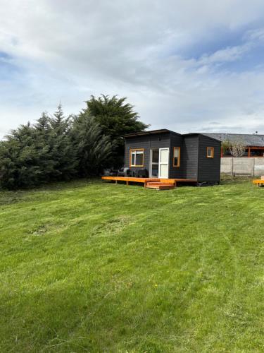 a small black tiny house on a grass field at Asoma Tiny House - Trevelin in Trevelin