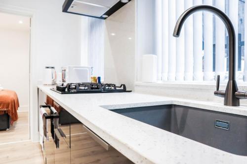 a kitchen with a sink and a stove at The Rye Retreat - 1BR Modern Design with Smart TV & Secure Underground Parking in Central High Wycombe HP13, Sleeps 3 in High Wycombe