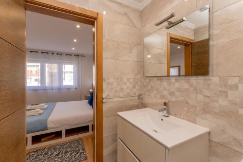 a bathroom with a sink and a mirror and a bed at LS Beach House in A dos Cunhados