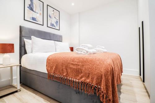 a bedroom with a bed with a orange blanket at The Rye Retreat - 1BR Modern Design with Smart TV & Secure Underground Parking in Central High Wycombe HP13, Sleeps 3 in High Wycombe