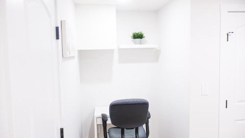 a black chair in a white room with a potted plant at A true Home away from Home in Calgary