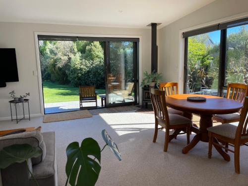 a living room with a wooden table and chairs at Warm, sun filled apartment in Albert Town